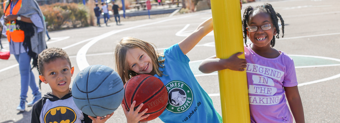 3 students on playground holding basketballs